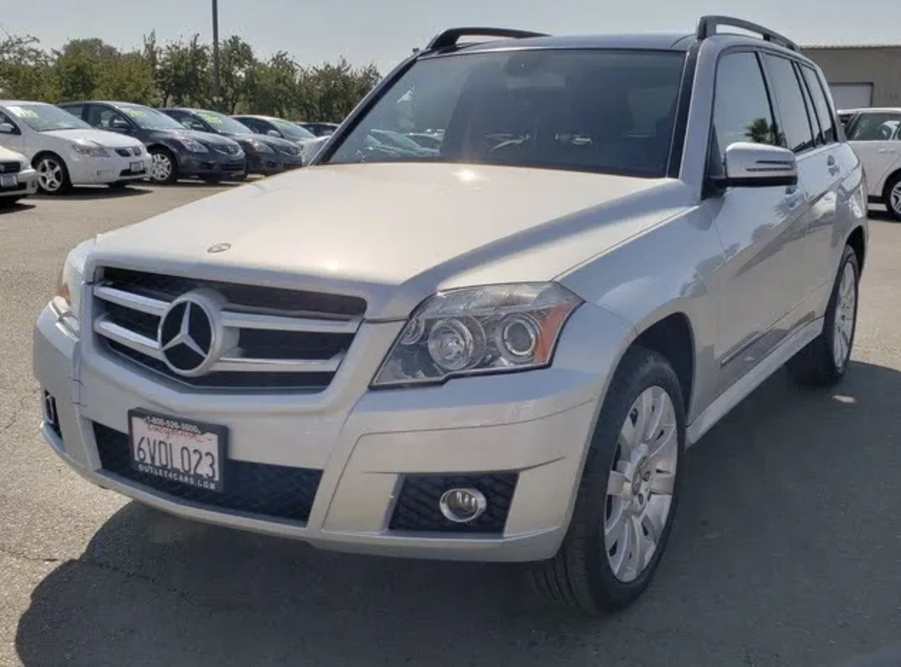 Mercedes-Benz GLK Phase 2 Iridium Silver immaculé stationné devant un garage moderne, design boxy distinctif
